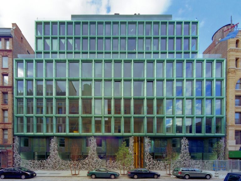 40 Bond Street exterior with its green glass-and-metal grid facade, sculptural street-level metalwork, and parked cars along the curb.