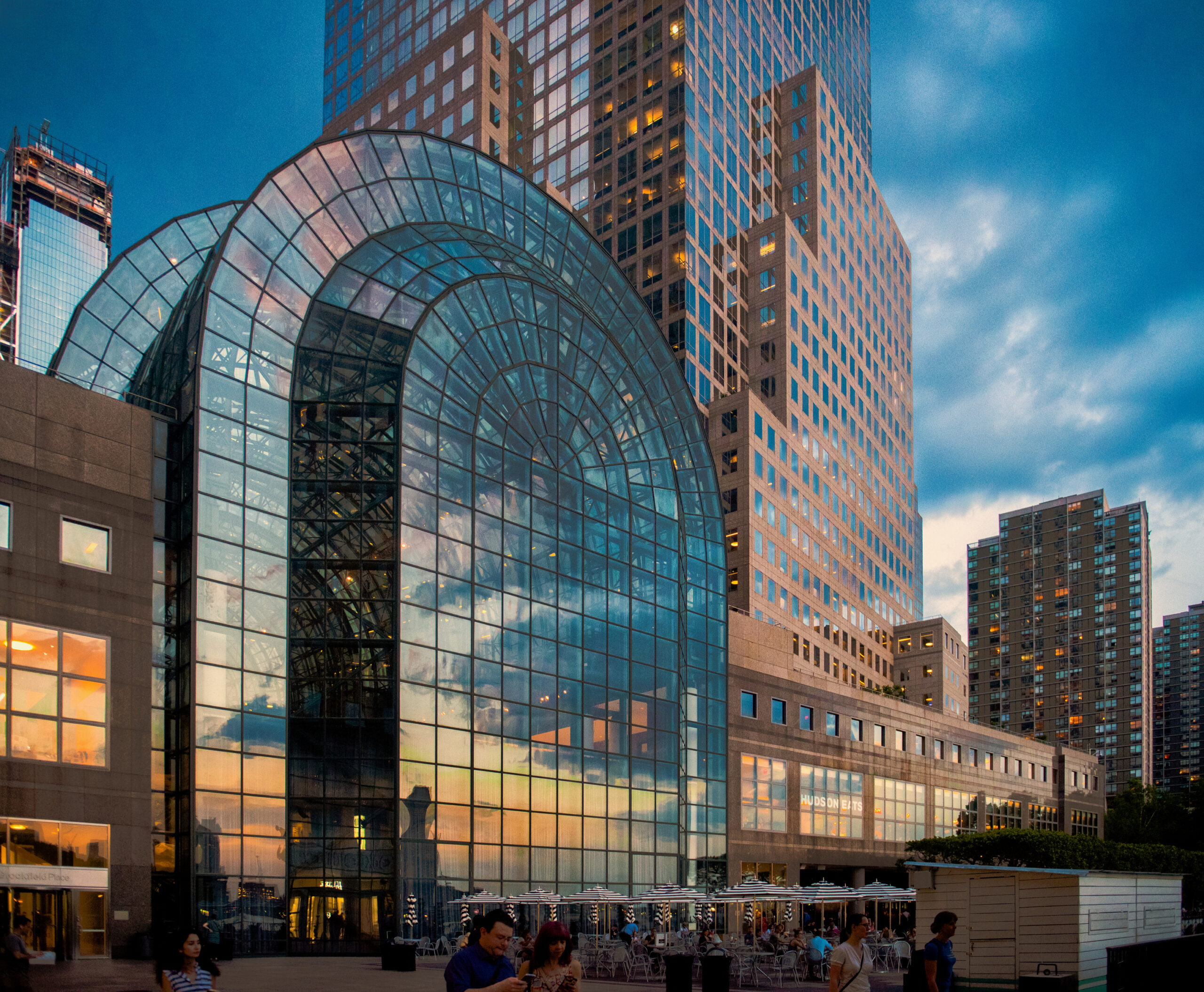 Brookfield Place exterior at dusk with its arched glass Winter Garden, surrounding towers, and people gathered on the plaza.