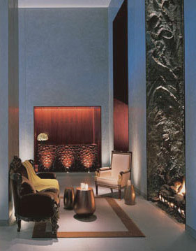 Clift Hotel lounge with pale blue walls, eclectic armchairs, small metallic tables, a dark marble fireplace, and a glowing red wall niche.