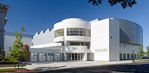 Crocker Art Museum exterior with a white modern facade, curved volumes, glass entry, and landscaped sidewalk under a clear blue sky.