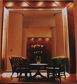 Delano Hotel lounge alcove with two dark armchairs, a low table, tall floral arrangement, and warm architectural lighting.