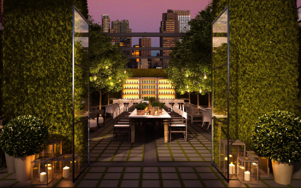EDITION Hotel rooftop terrace at dusk with tall hedges, candlelit lanterns, a long communal table, and an illuminated bar against the skyline.