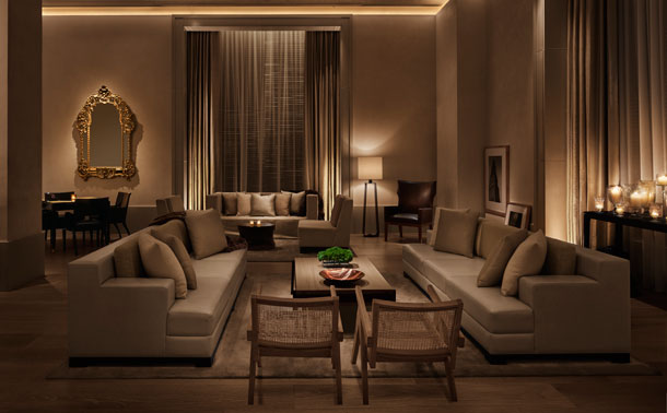 New York EDITION lounge with cream sofas, tall draped windows, an ornate gold mirror, and warm low lighting.