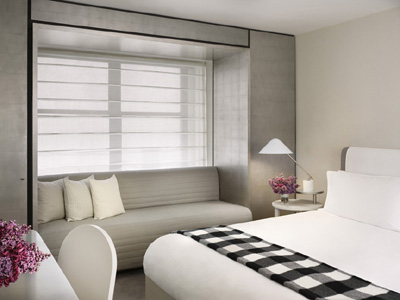 Morgans Hotel guest room with a white bed, black-and-white checkered throw, gray window bench, and soft neutral finishes.