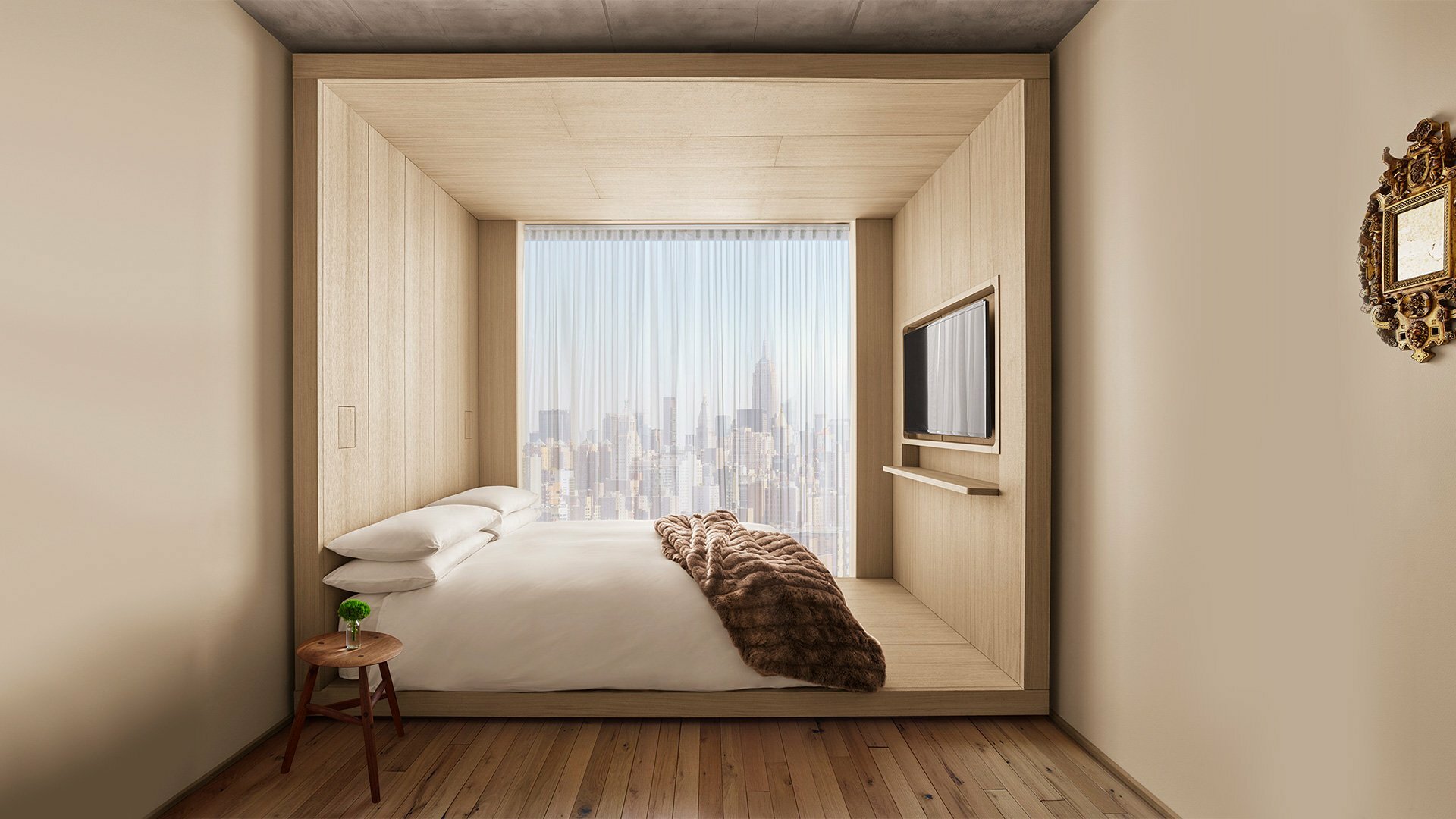 PUBLIC Hotel guest room with a minimalist bed set into a pale wood alcove, wall-mounted TV, and large window framing the Manhattan skyline.