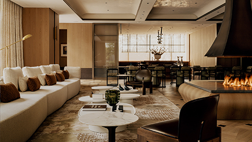 Contemporary Springs Residences lounge with a long cream sofa, marble coffee tables, dining area, and open fireplace.