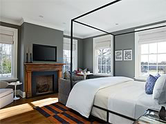 Topping Rose House guest room with a black four-poster bed, fireplace, pale walls, and warm wood flooring.