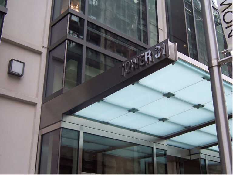 Tower 31 entrance with a glass-and-metal canopy, modern facade, and prominent TOWER 31 signage.